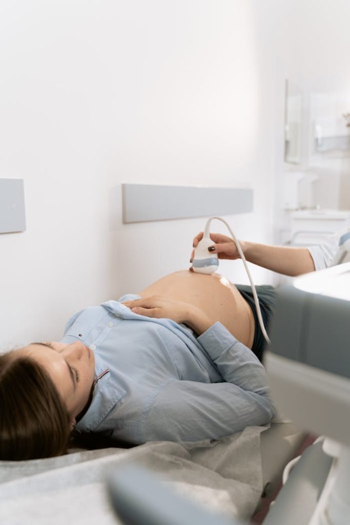 Pregnant woman receiving ultrasound scan in clinic setting.
