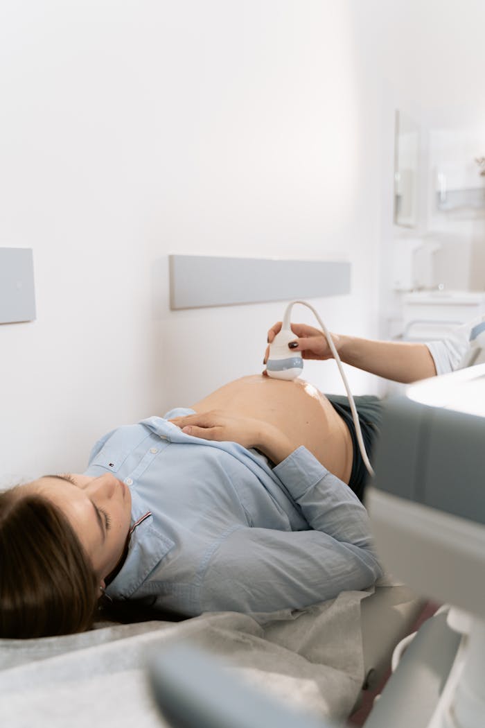 Pregnant woman receiving ultrasound scan in clinic setting.